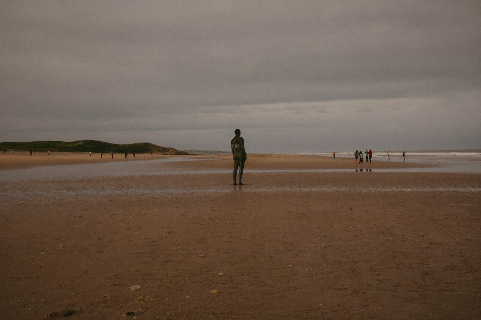Father and two young children walking Crosby beach at low tide